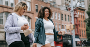 Two friends walking and talking with coffee in a city | eating disorder.care